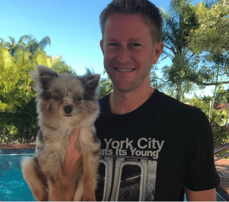 Scott Keever, the best looking SEO expert in Miami, holding a small dog by a pool